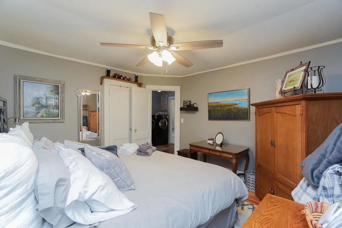 A spacious bedroom with a large bed adorned with soft linens, complemented by a wooden armoire and tastefully chosen artwork. The room exudes calmness and offers plenty of personal space for rest or quiet moments.