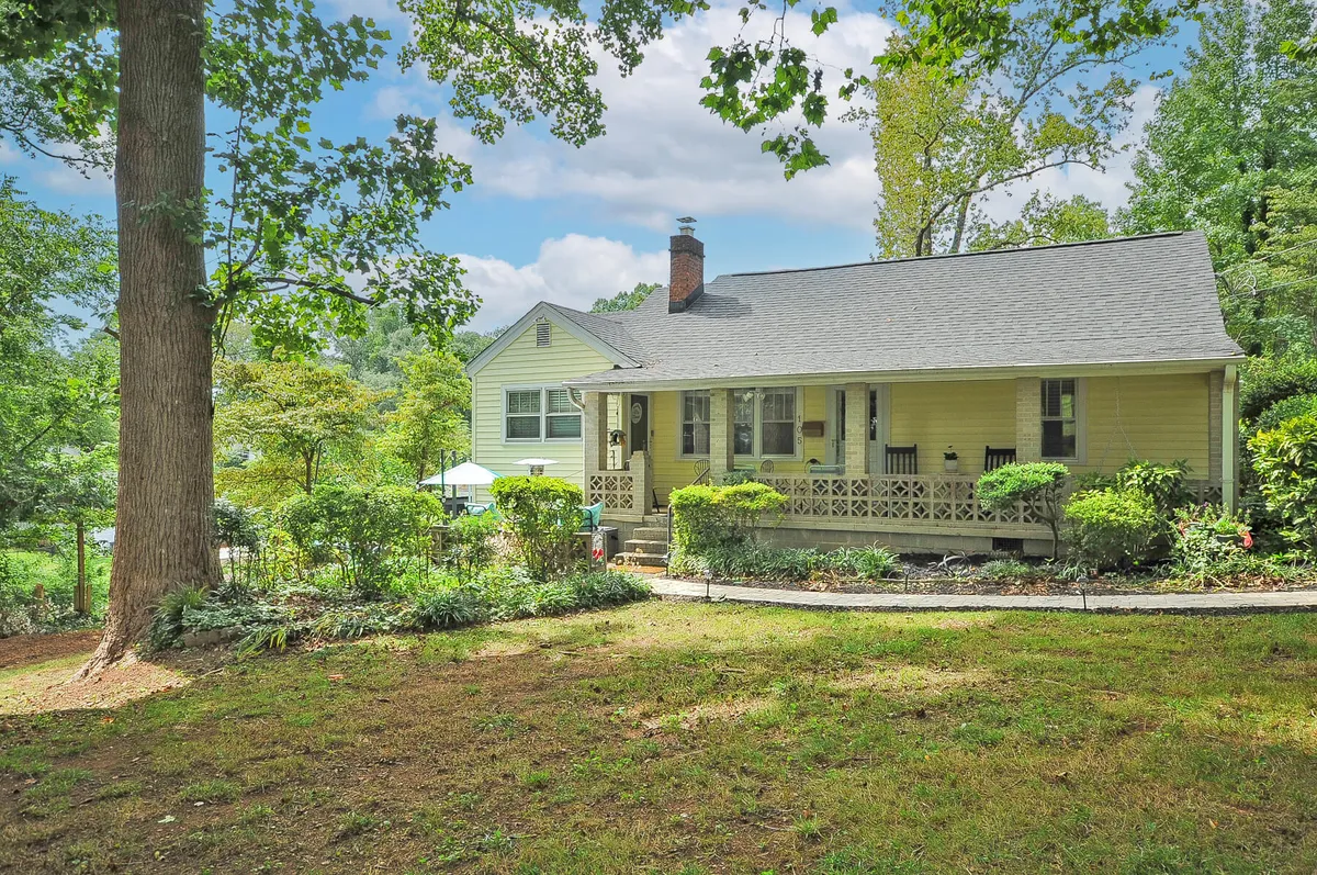This image features a charming yellow house nestled amid lush greenery, with a welcoming front porch and a walking path leading up to it. The tranquil surroundings evoke a sense of seclusion and intimacy, perfect for a romantic retreat. The porch suggests a spot for morning coffee while immersed in nature.